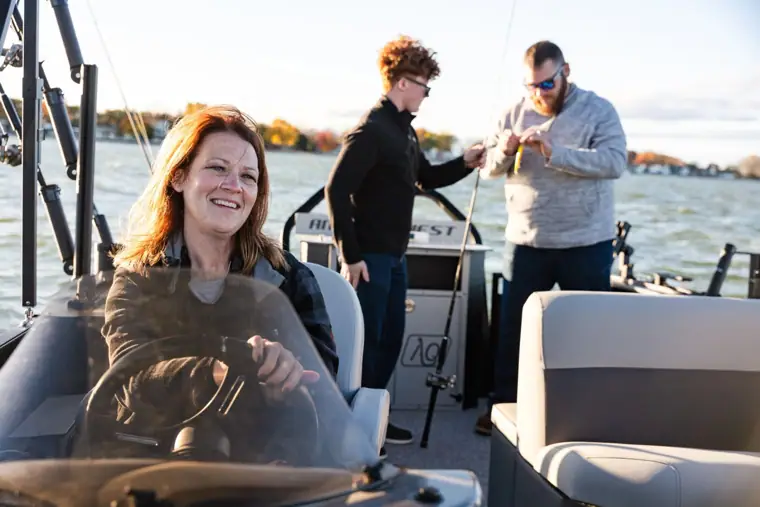 Captain at the helm with family fishing behind